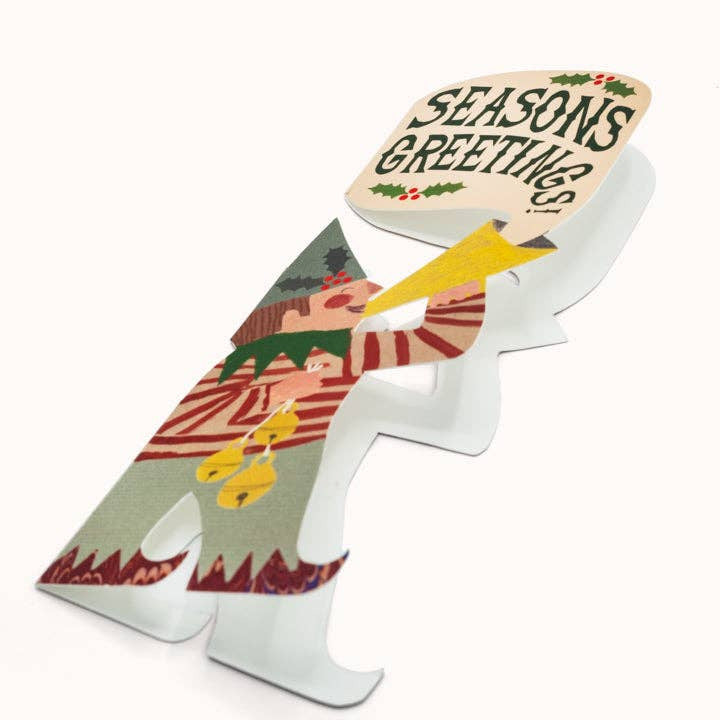 A decorative card shaped like an elf, featuring a cream-colored top section with 'SEASONS GREETINGS' in black script, and a tree-patterned seat with red, green, yellow, and white details.