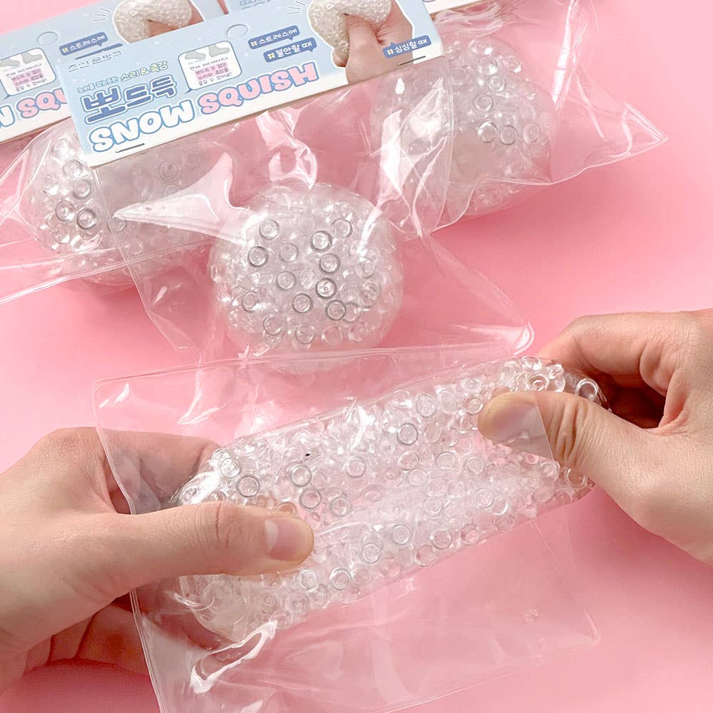 Clear squishy balls in packaging with a pink background