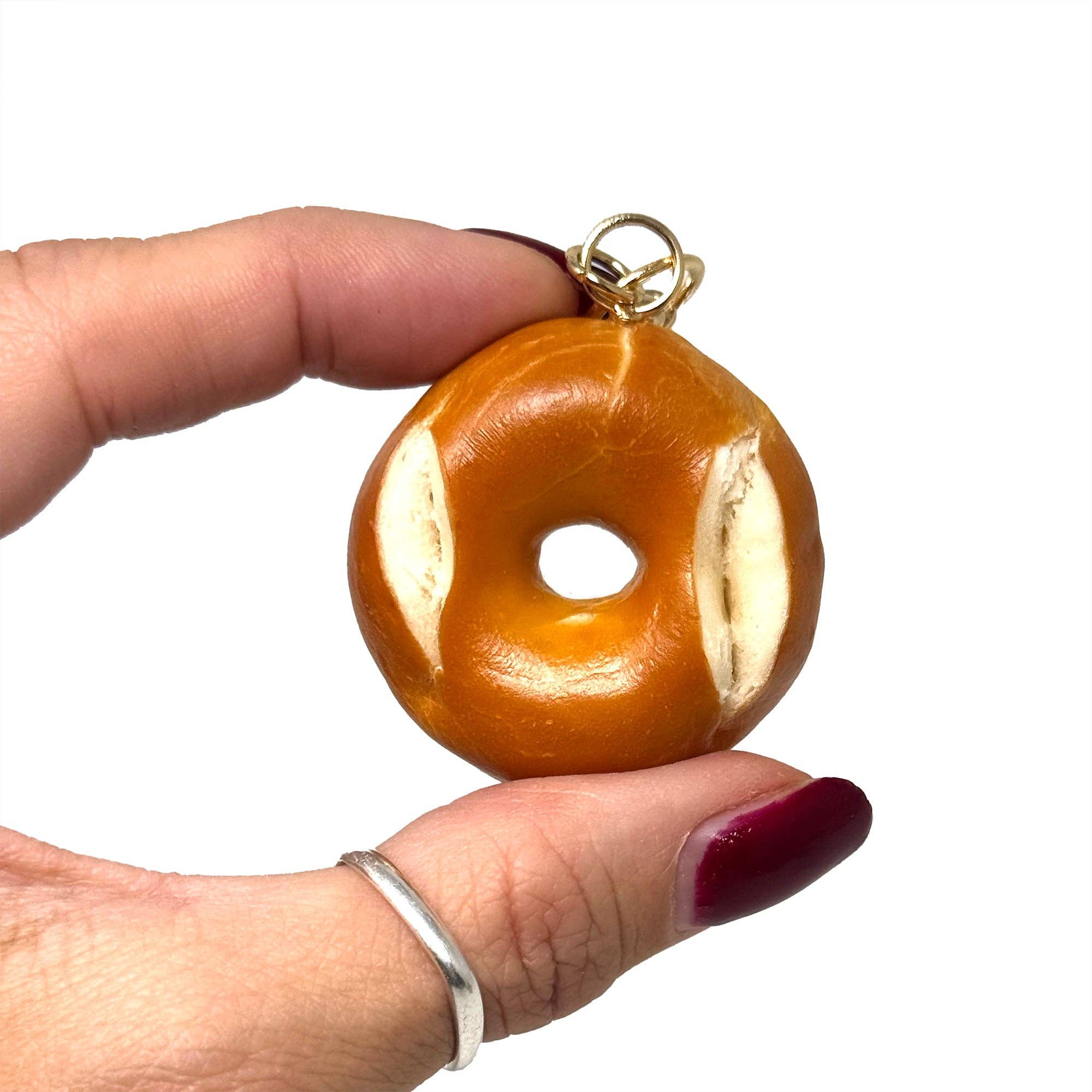 Hand holding a bagel-shaped keychain against a white background