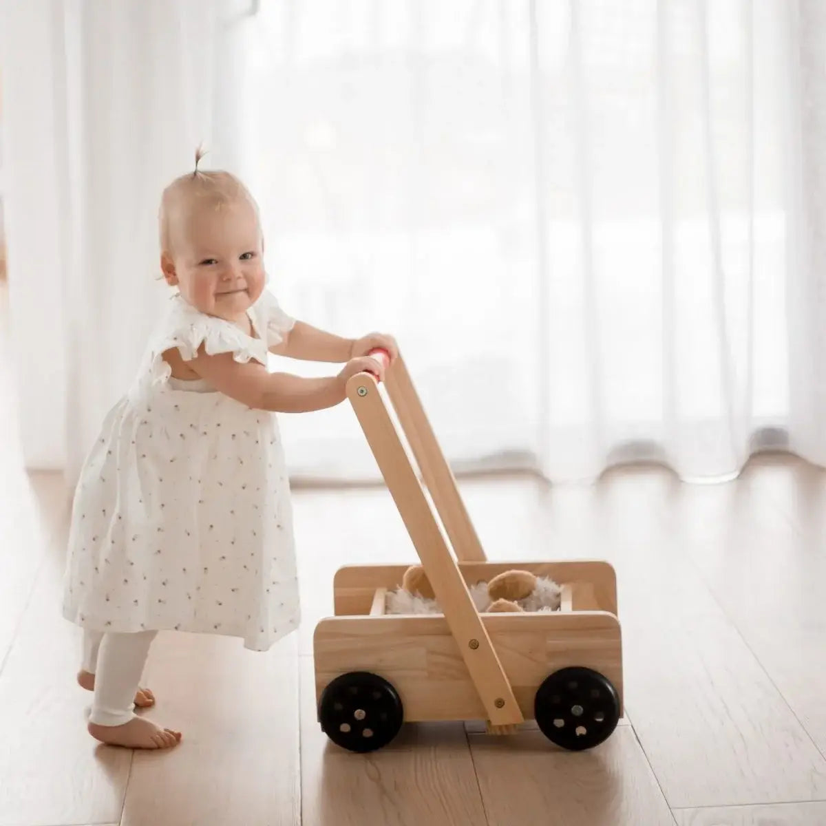 Child playing with a wooden toy cart in a bright room