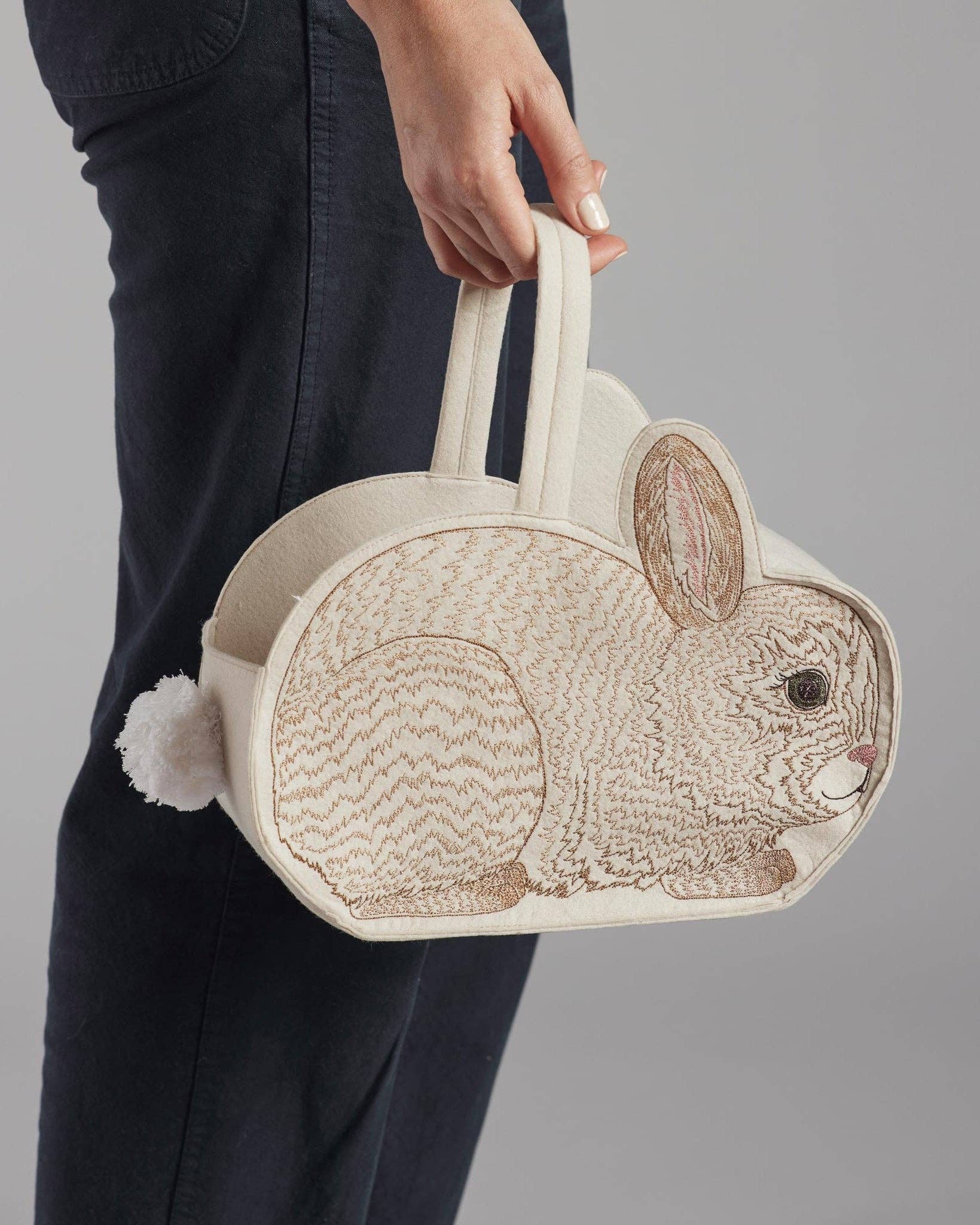 Handbag shaped like a rabbit held by a person against a gray background