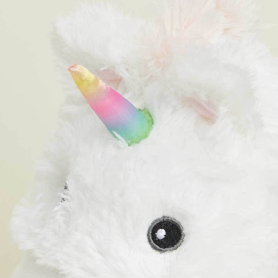 Close-up of a plush unicorn toy with a rainbow horn on a light background