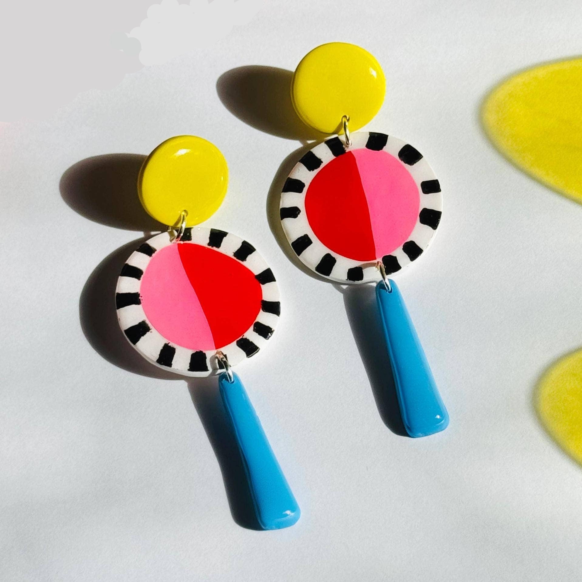 Colorful earrings with pink, yellow, and blue accents on a white background.