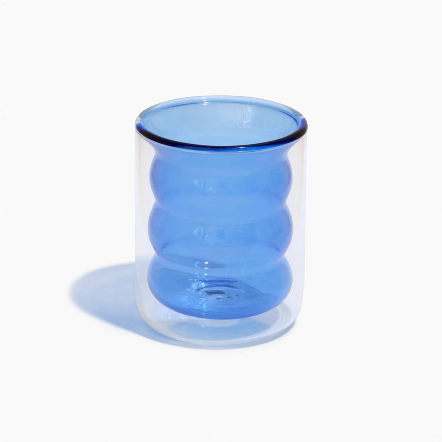 Clear glass mug with blue interior and rim on a white background