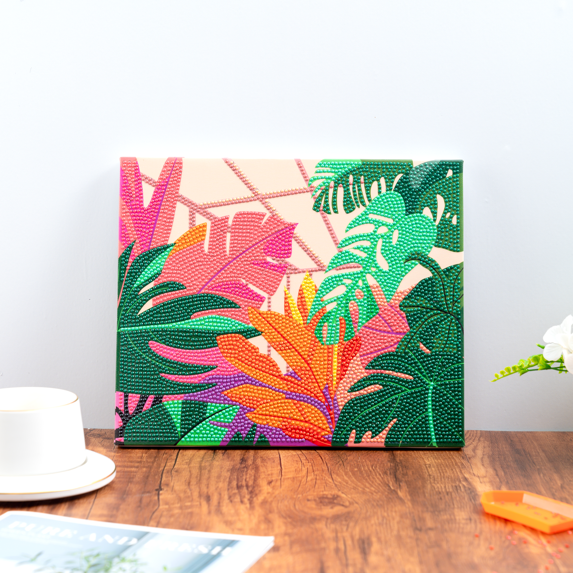Colorful tropical leaf patterned painting on a wooden table with a white wall background