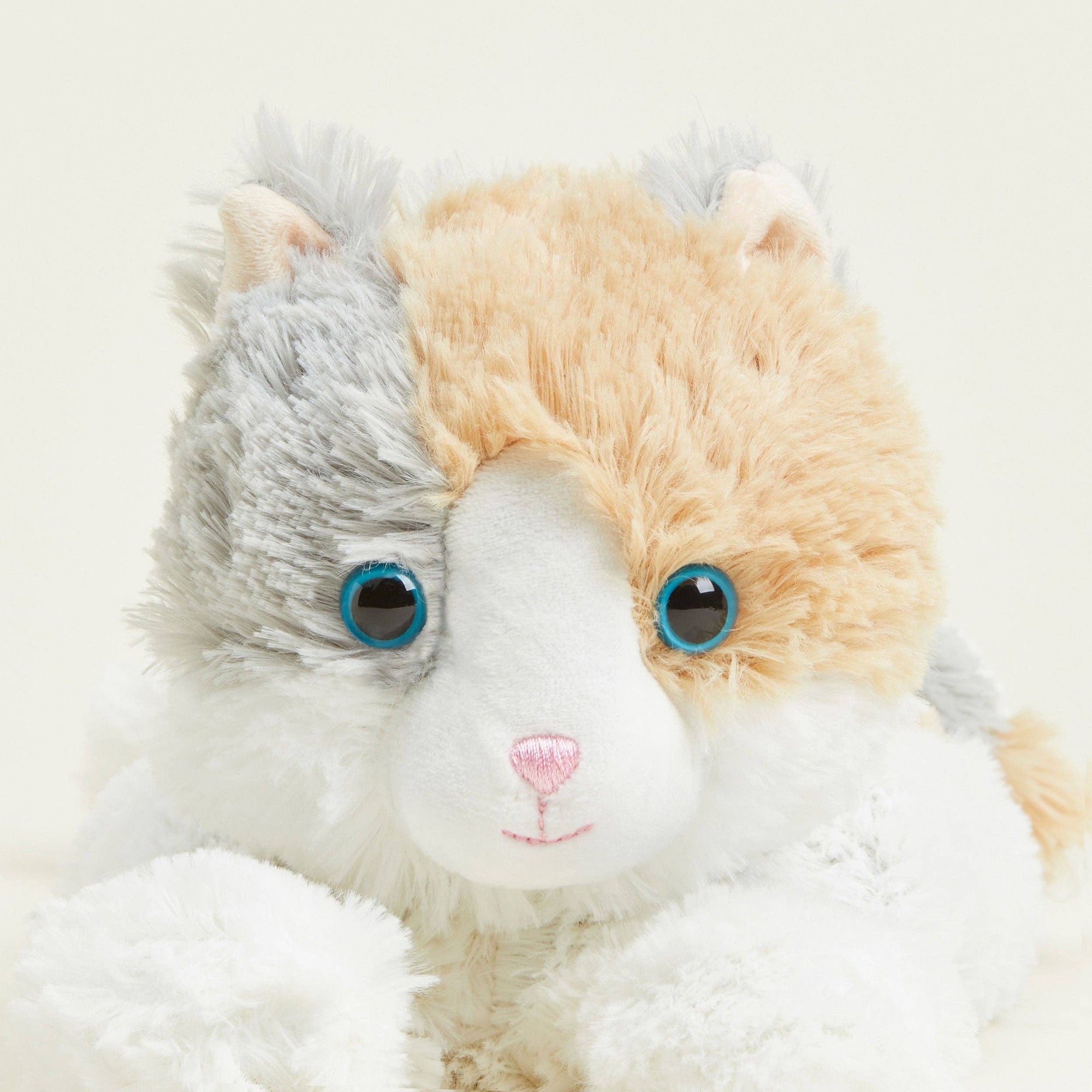 Plush toy with a split face, one side gray and one side beige, on a light background.