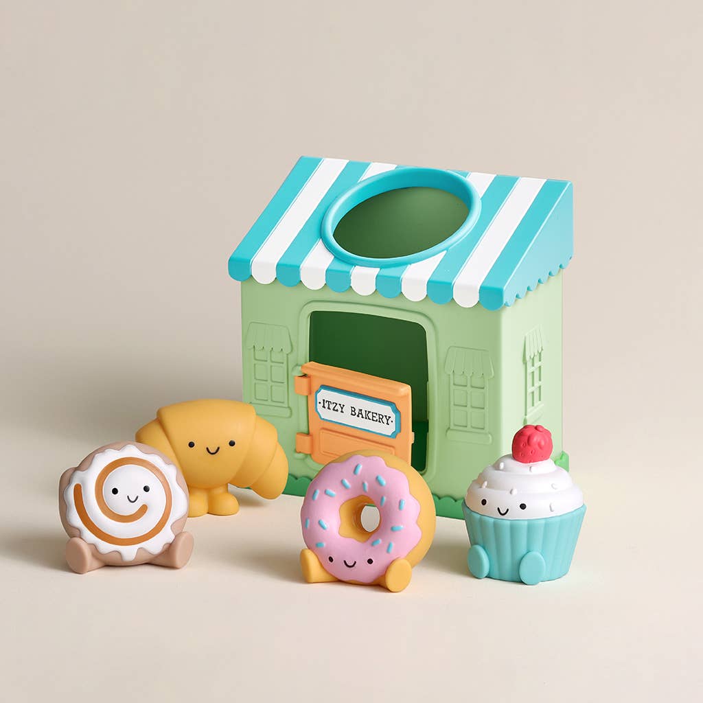 Toy bakery set with a striped green and blue roof, featuring a donut, cupcake, and other items on a beige background.