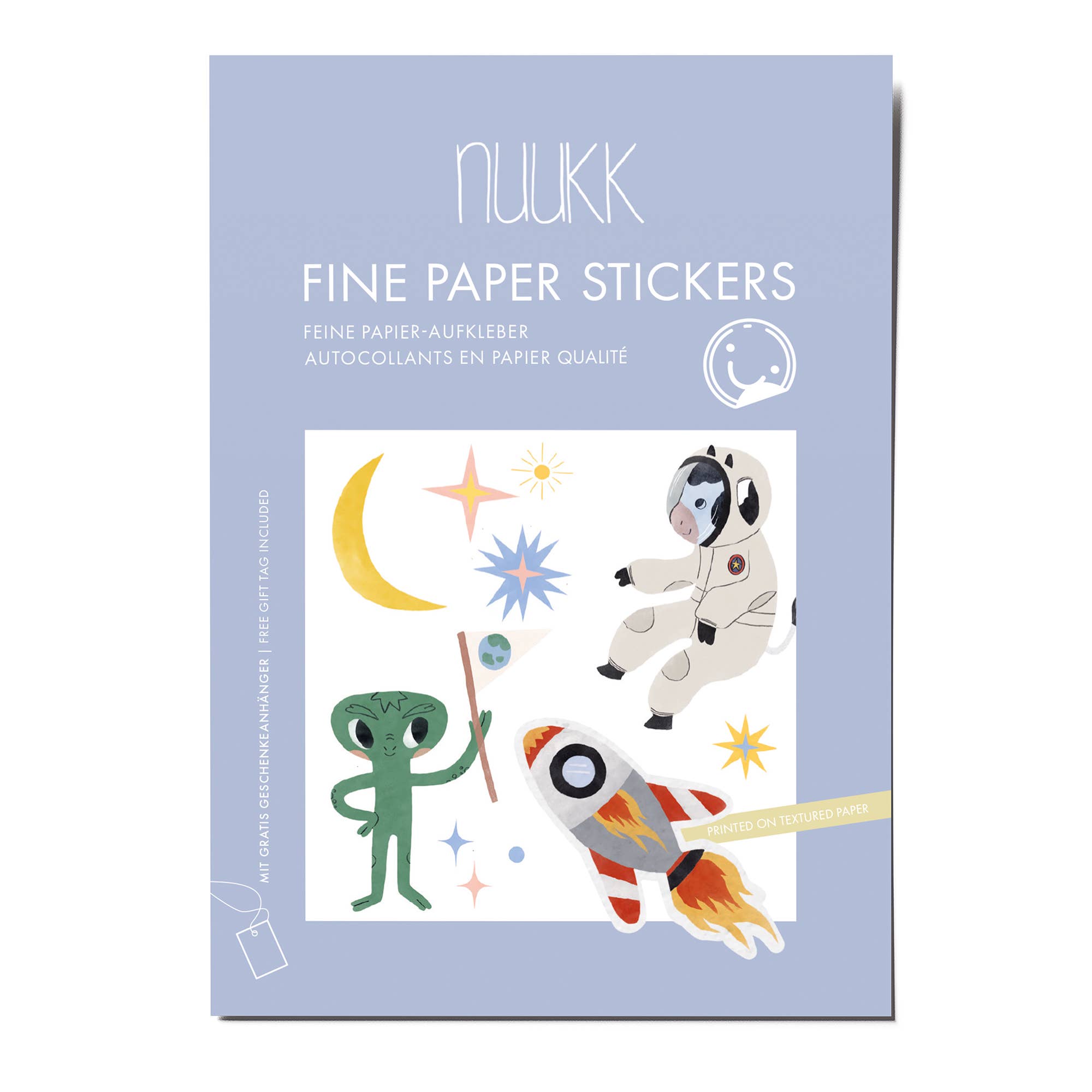 A package of Nuukk Fine Paper Stickers featuring a light blue-gray background with white text and a central illustration of outer space elements including an astronaut, a green alien, a crescent moon, stars, and a rocket.