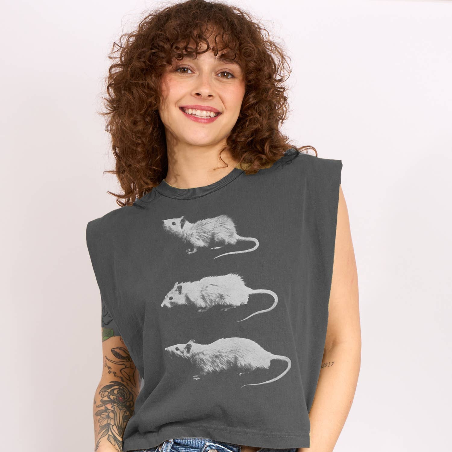 Woman wearing a dark gray sleeveless shirt with white rat graphics on a plain background