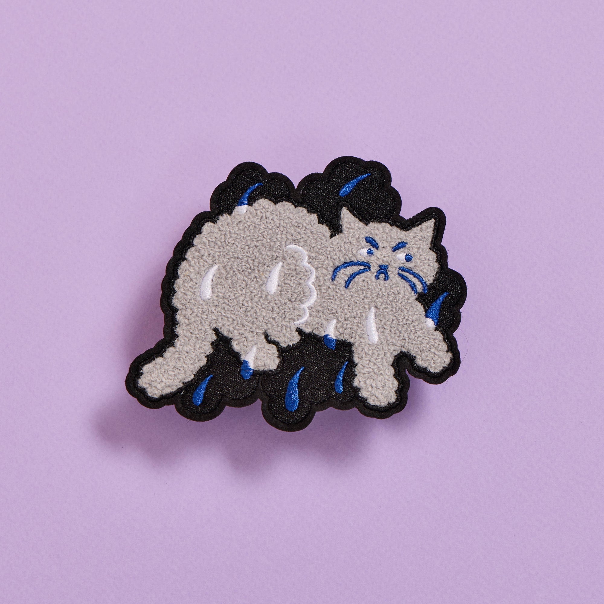 Embroidered patch of a cat with black hair on a purple background