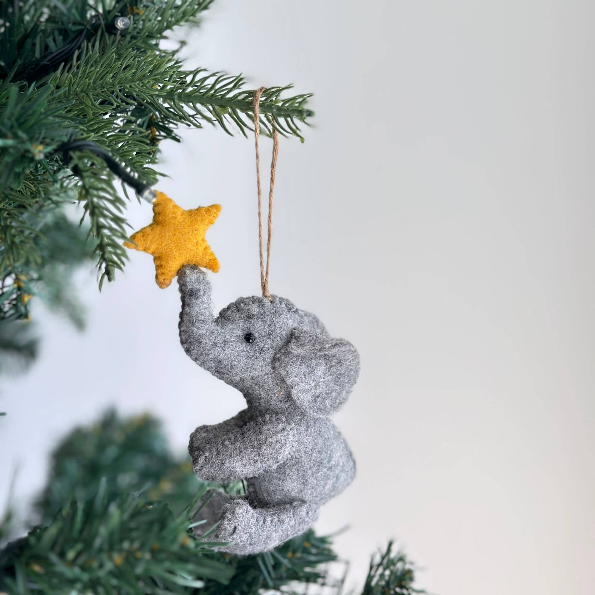 Decorative elephant ornament with a yellow star on a Christmas tree.