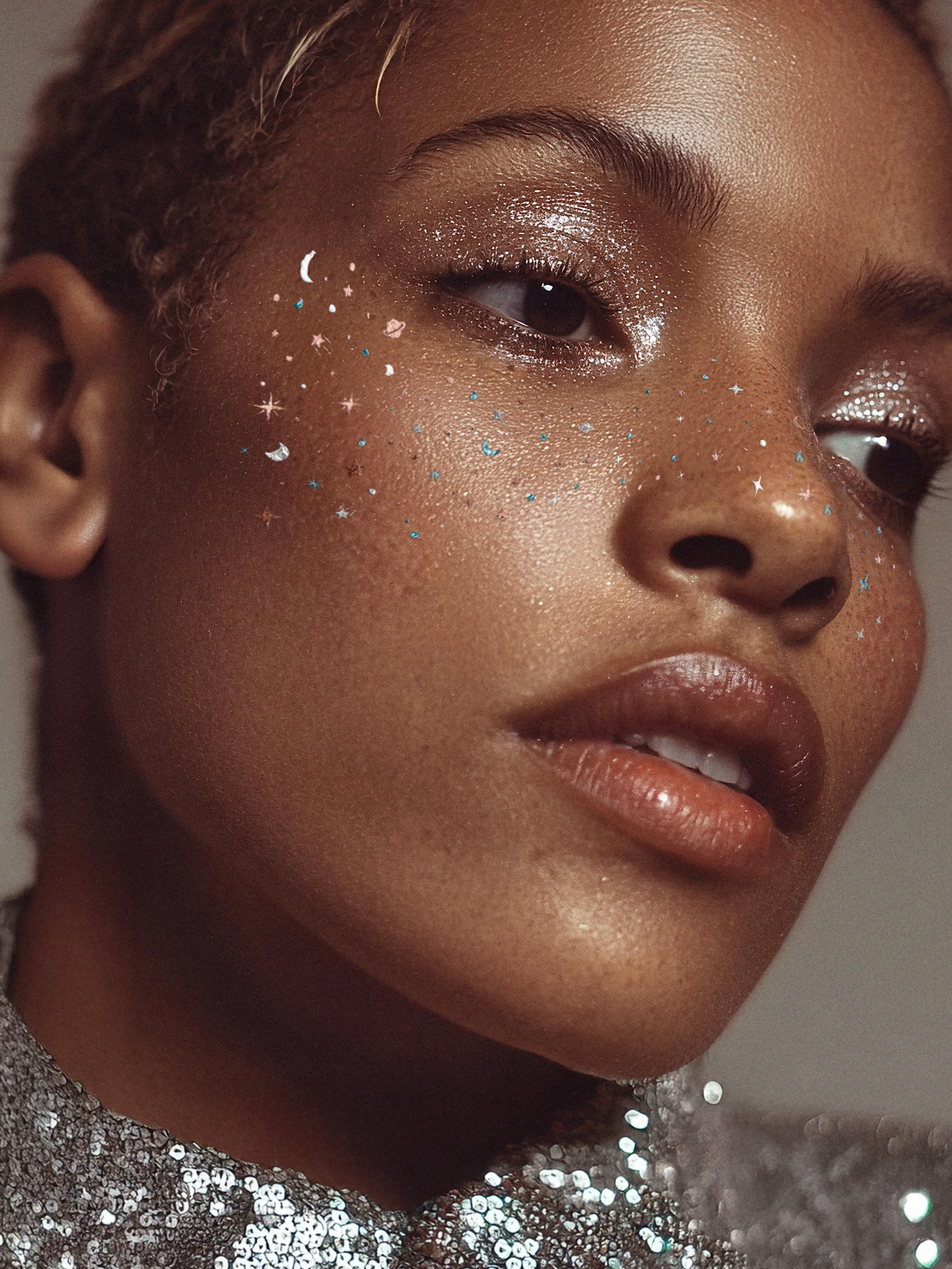 Close-up of a person with glitter on their face wearing a sequin outfit.