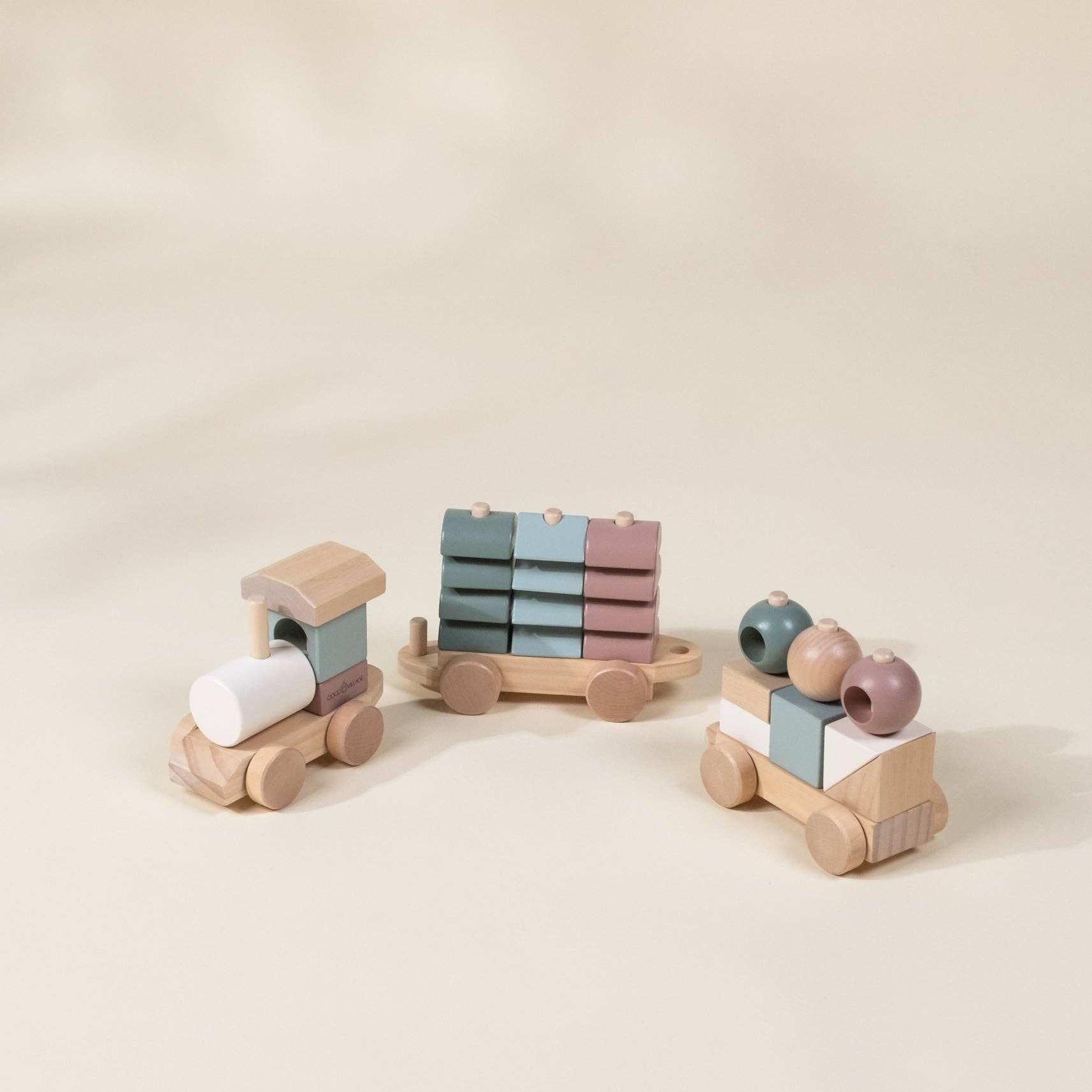 Set of wooden toys including a train and cars on a beige background