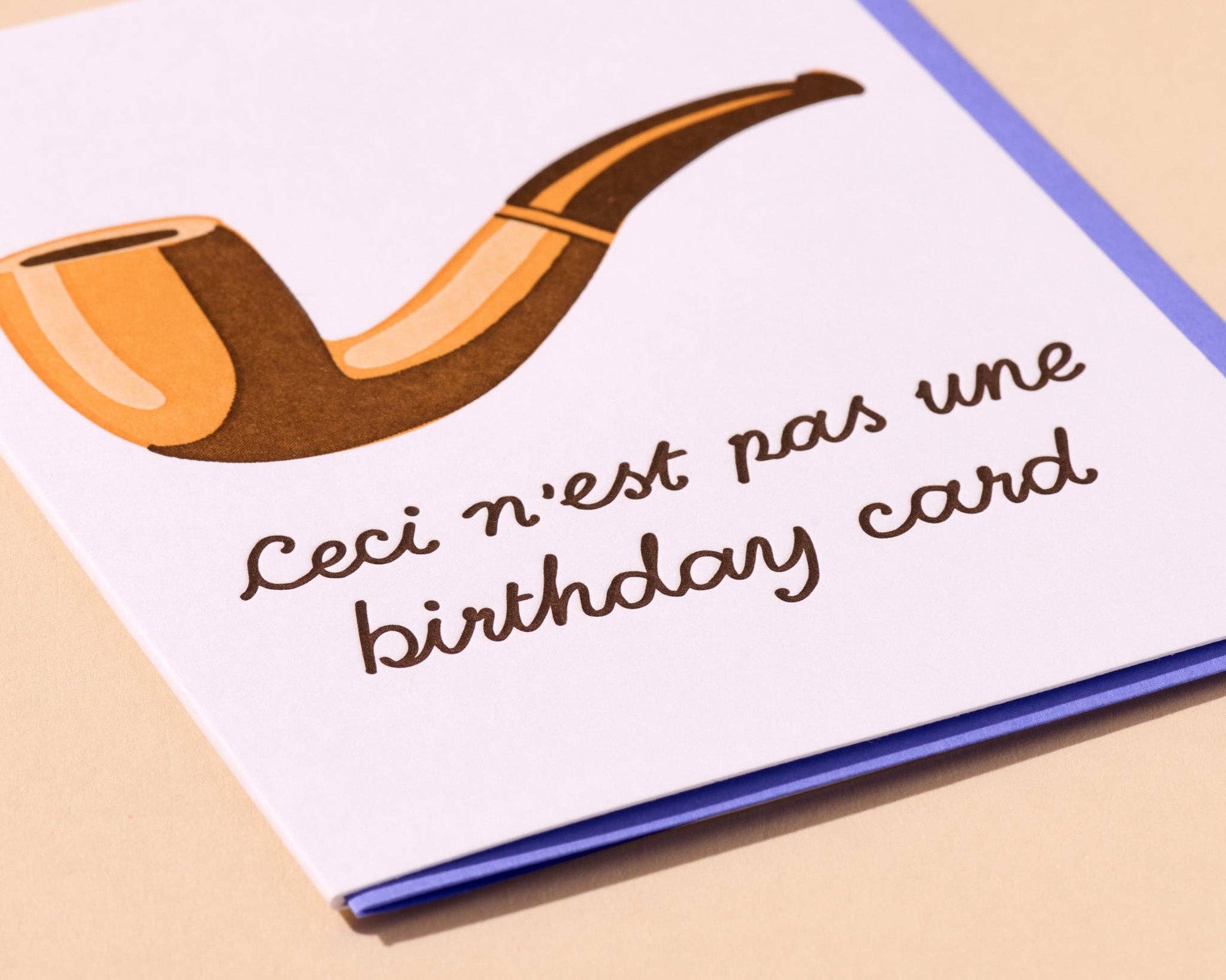 Card with a smoking pipe illustration and text 'Ceci n'est pas une birthday card' on a beige background