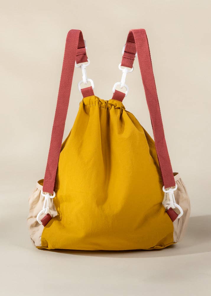 Yellow drawstring bag with red straps on a beige background