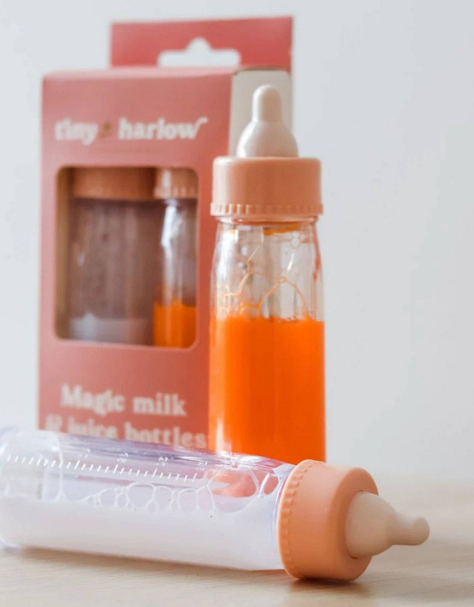Two baby bottles with orange liquid and a packaging box labeled 'clay & harlow' on a light background.
