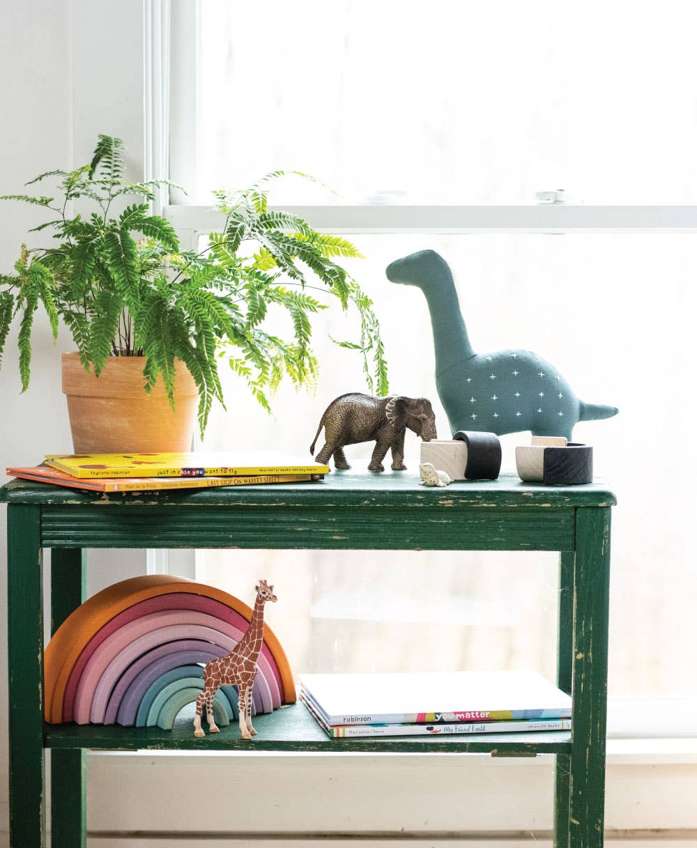 Green table with children's toys and a plant in a bright room