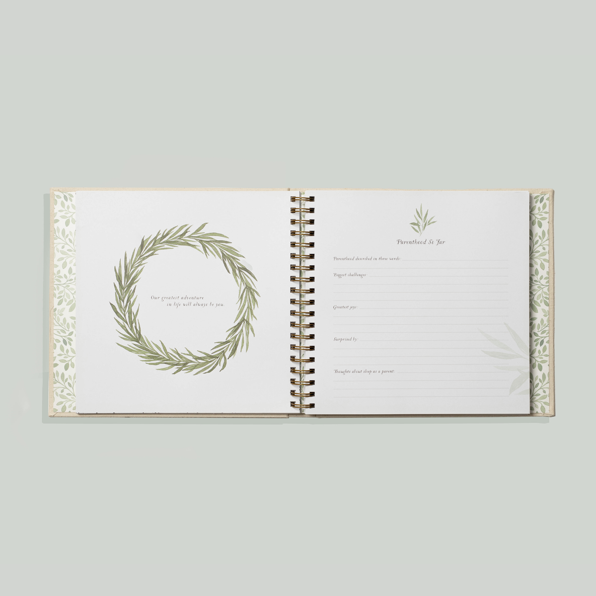 Open book with decorative wreath design on a light gray background