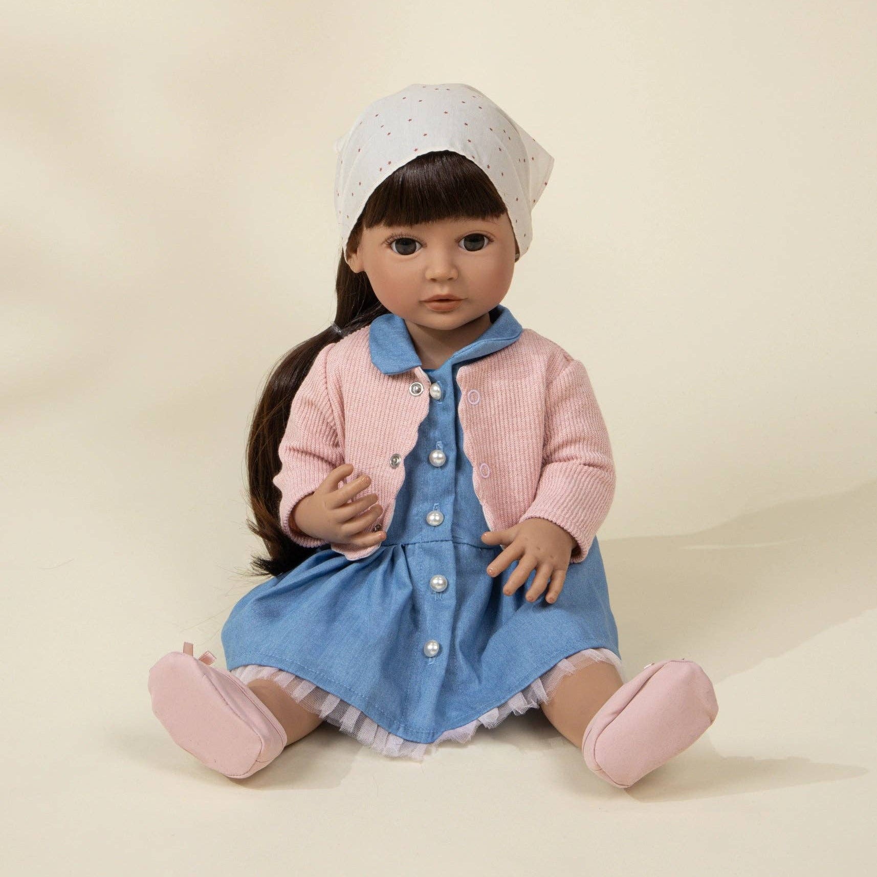 Doll wearing a pink jacket and blue dress with a white hat on a beige background