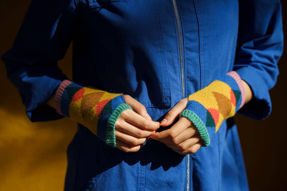 Person wearing a blue jacket with colorful knit arm warmers.
