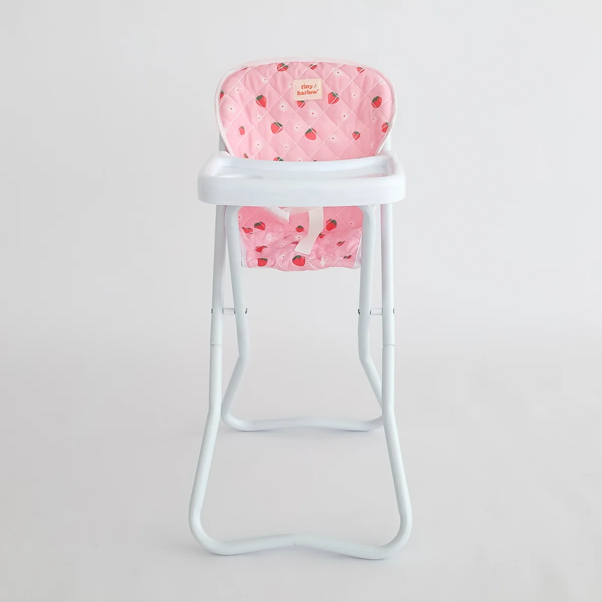 Pink high chair cover with white polka dots on a white background