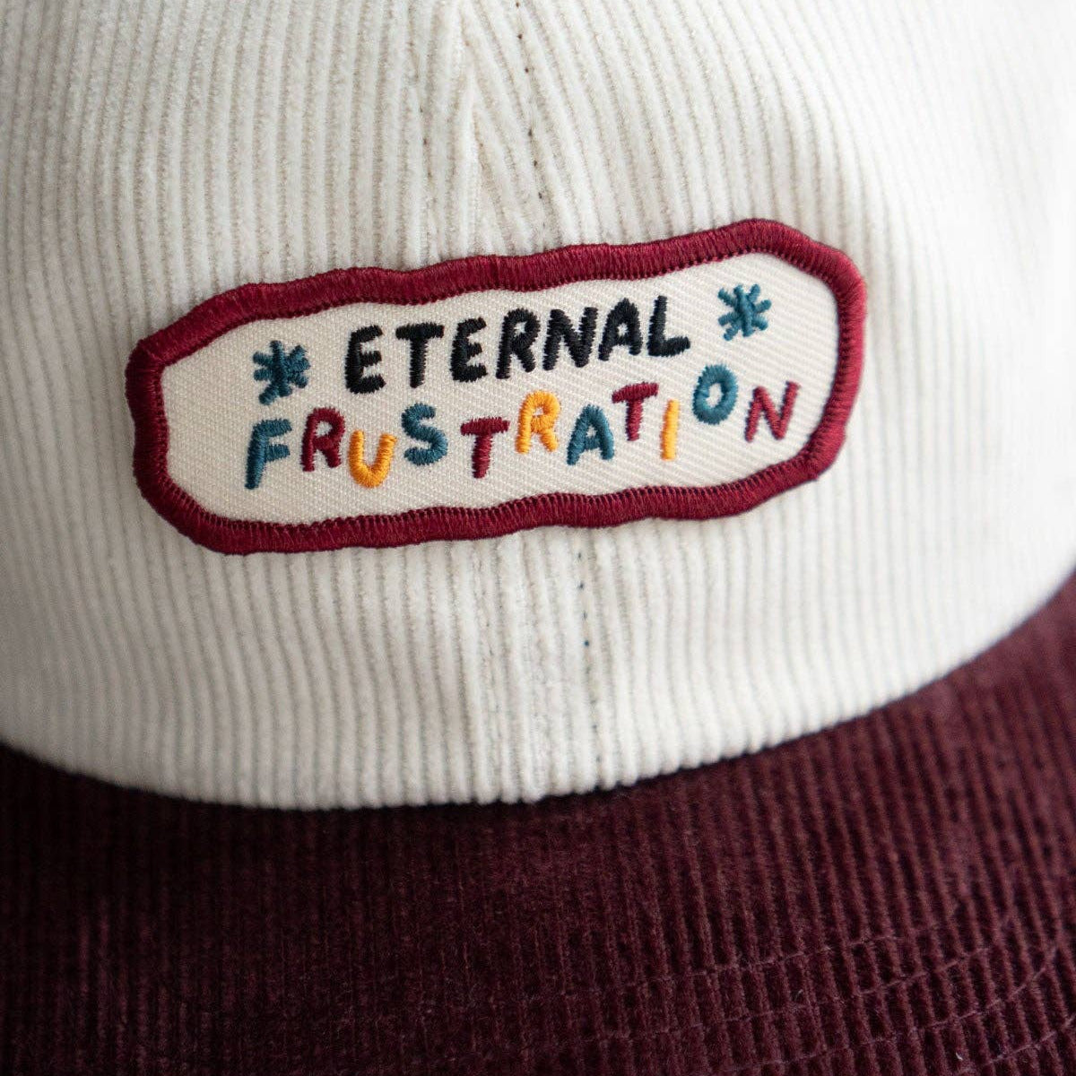 Cap with 'Eternal Frustration' patch on a white background