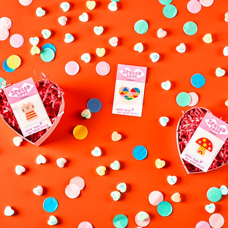 Heart-shaped boxes with cards on a bright orange background with colorful confetti