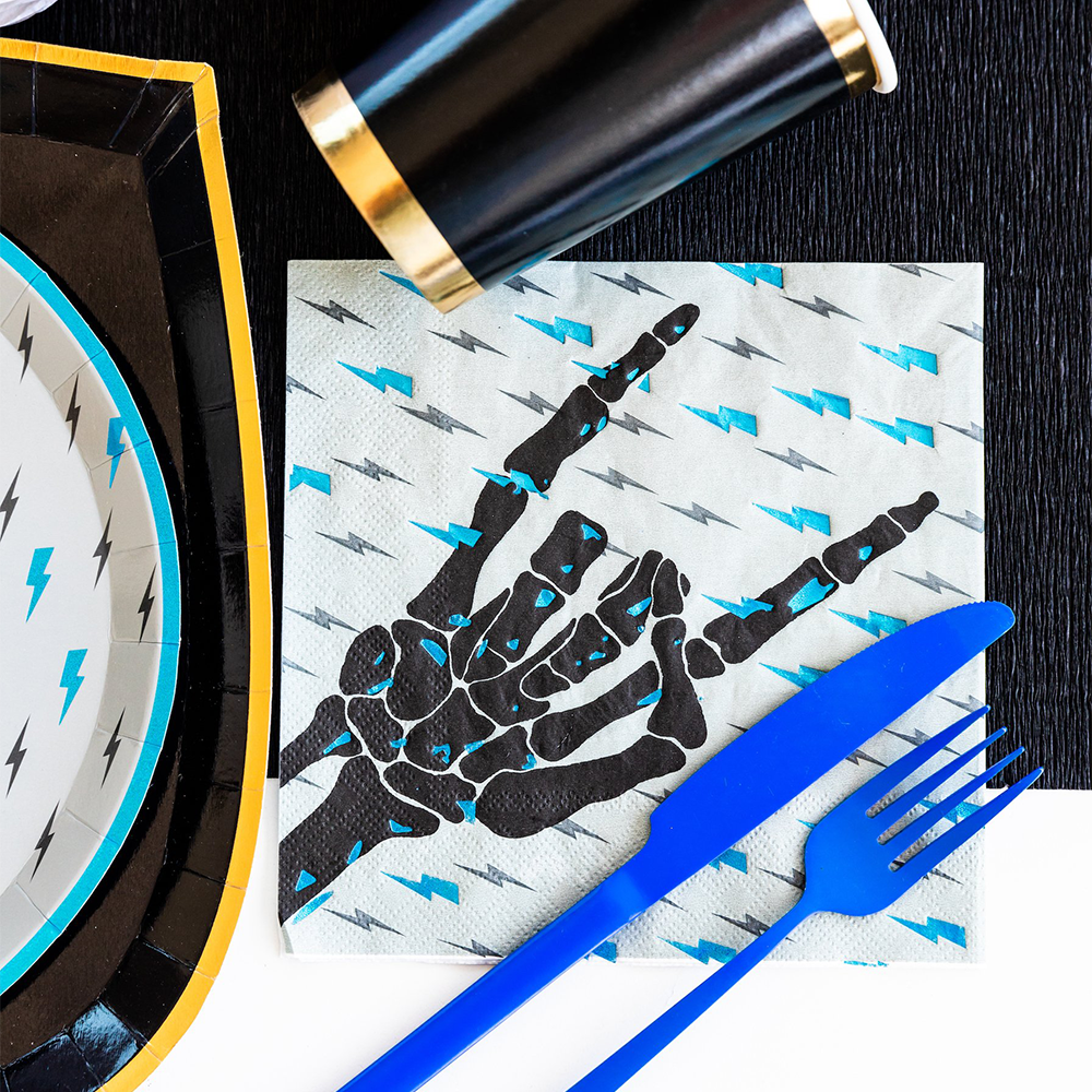 Napkin with skeleton hand design on a black surface with blue cutlery.