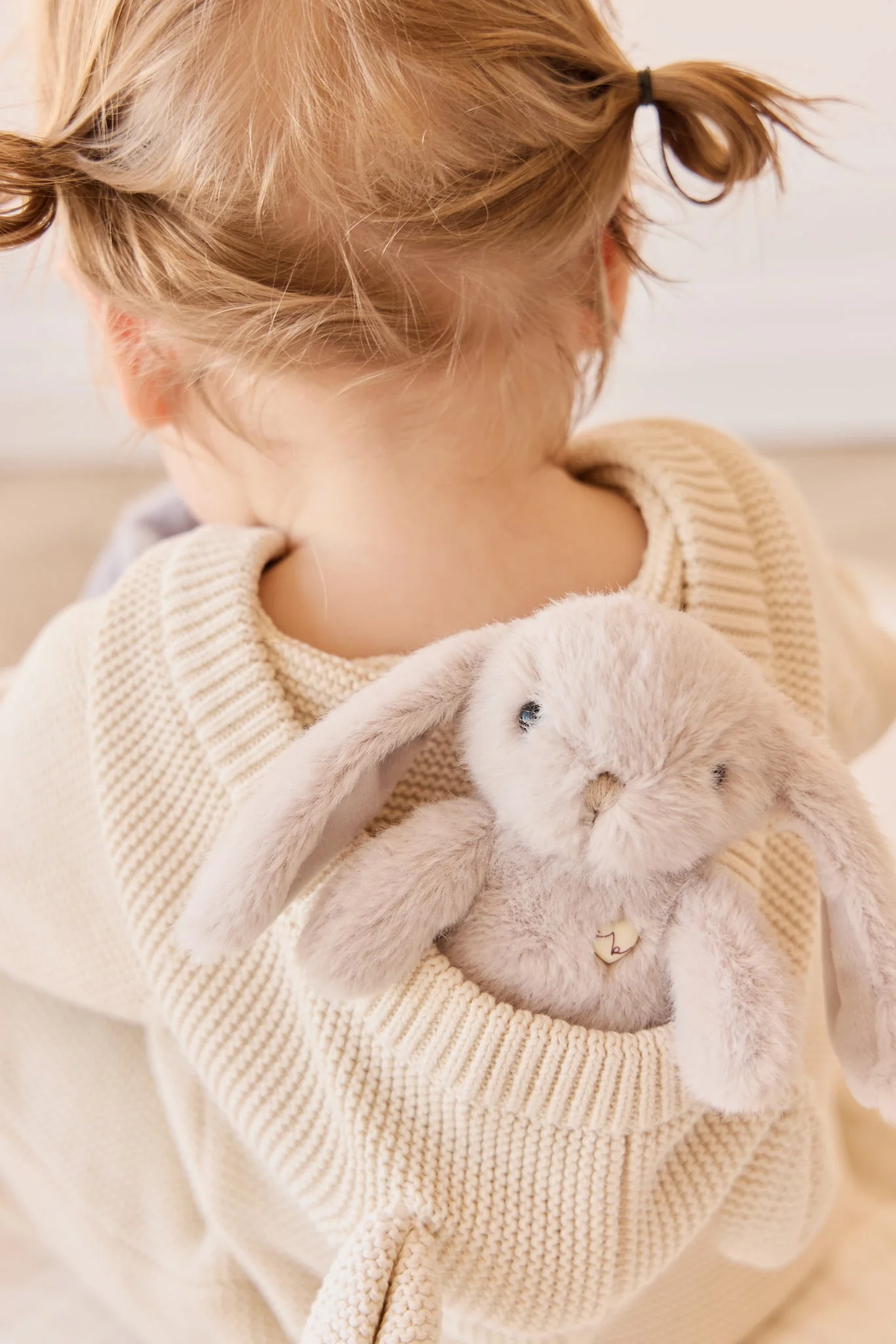 Child holding a plush bunny toy with a neutral background
