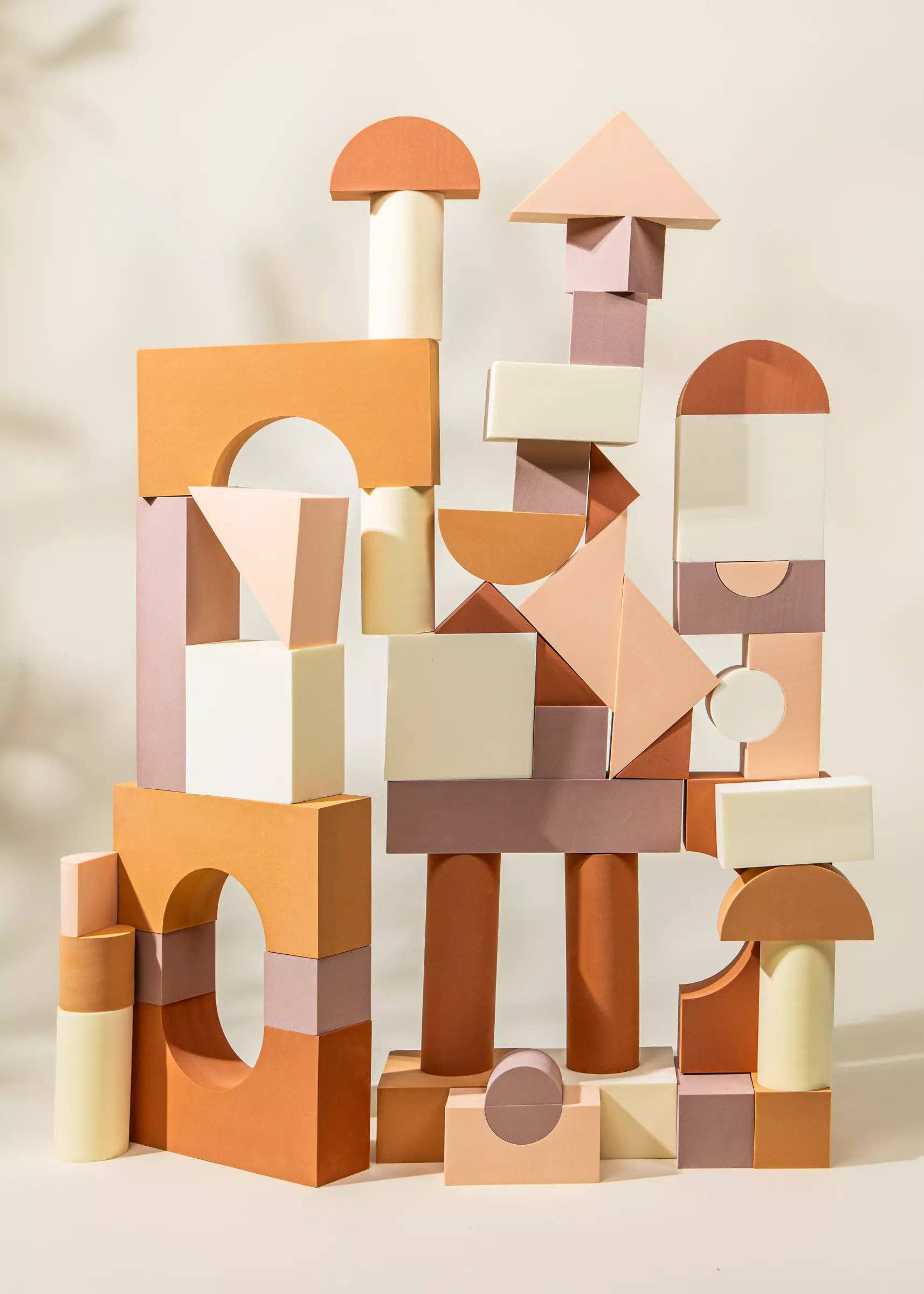 Stack of geometric wooden blocks in various shapes and colors on a neutral background