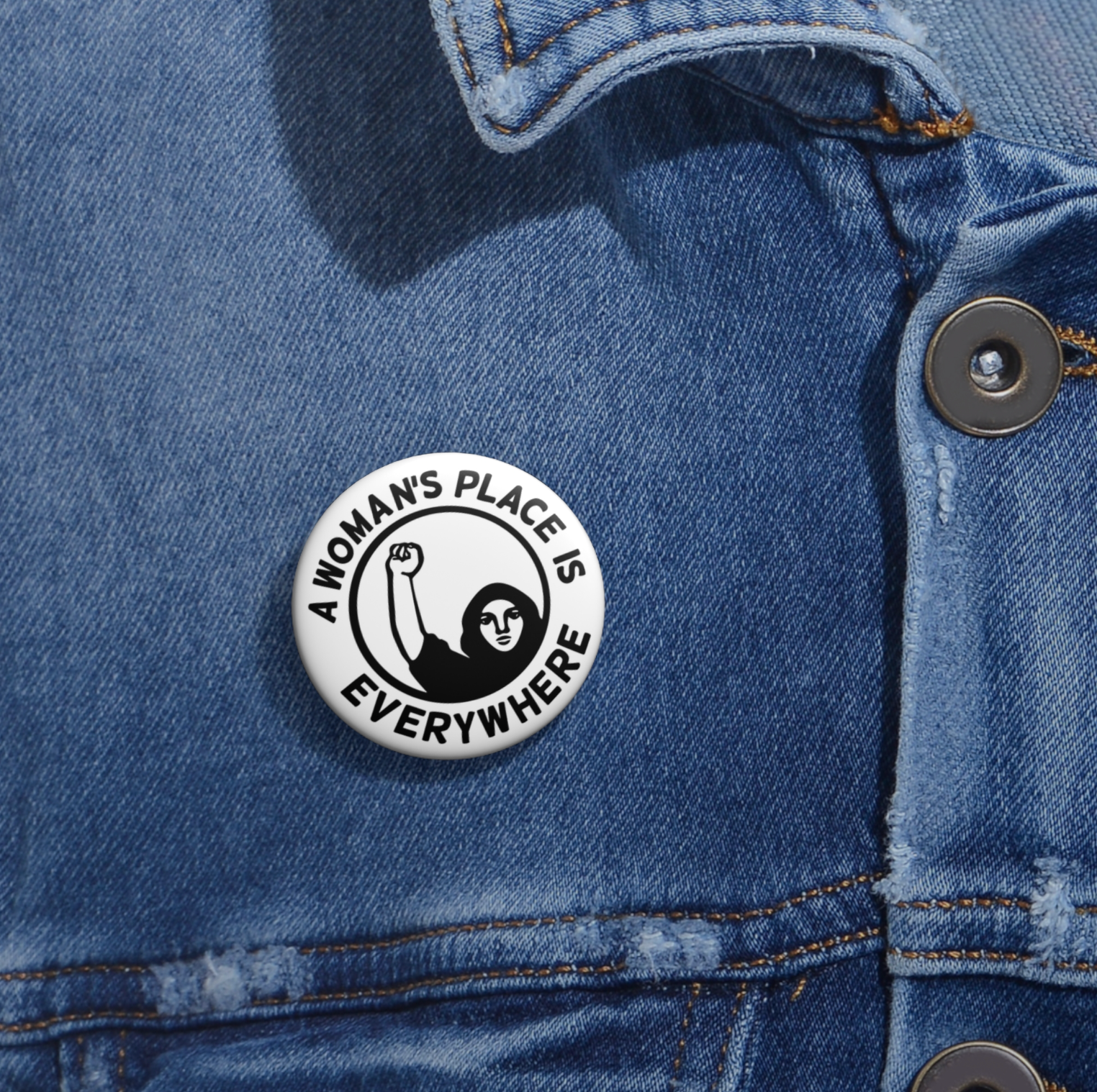 Button with 'A Woman's Place is Everywhere' text on a denim jacket