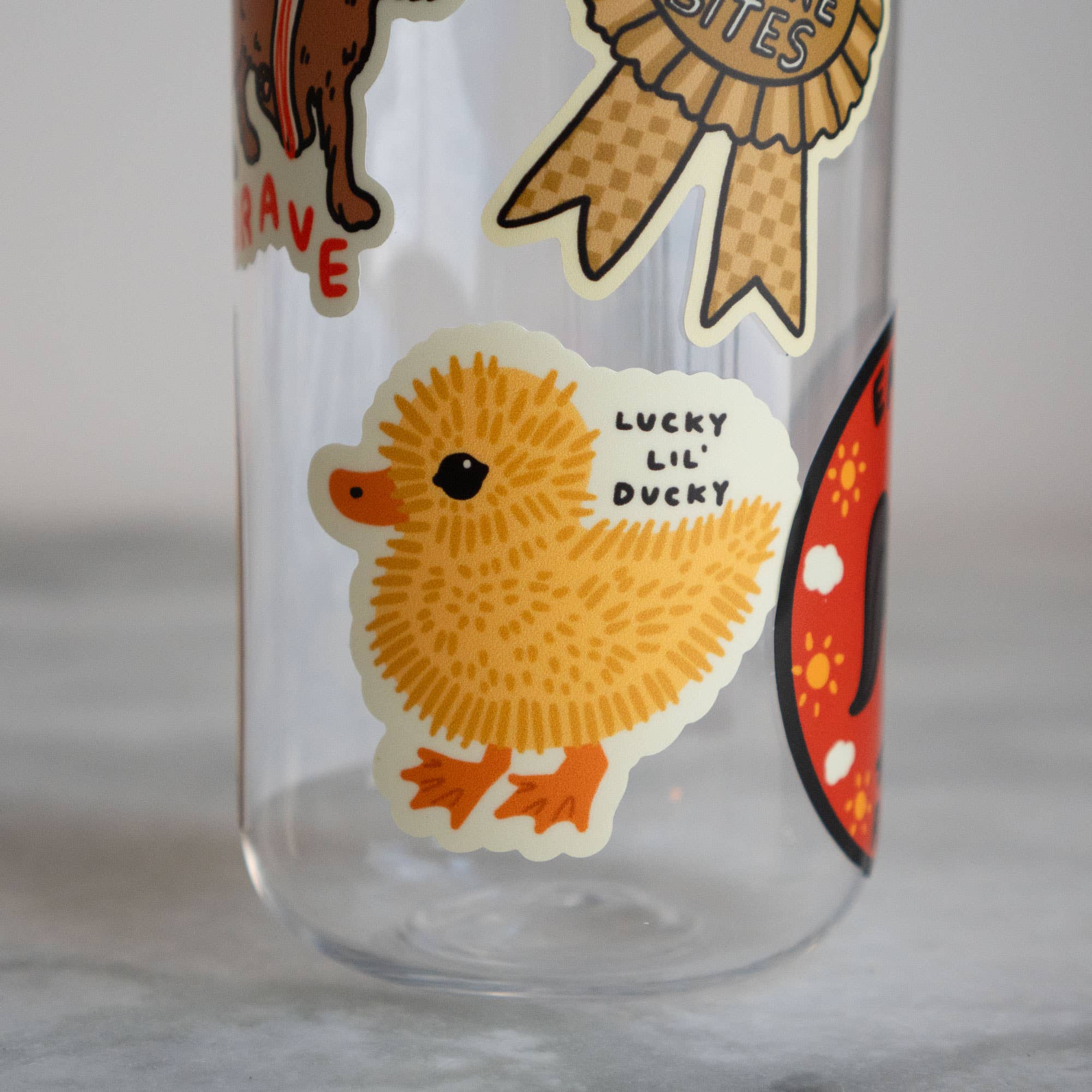 Clear glass with a yellow duck sticker labeled 'Lucky Lil' Ducky' on a light gray background