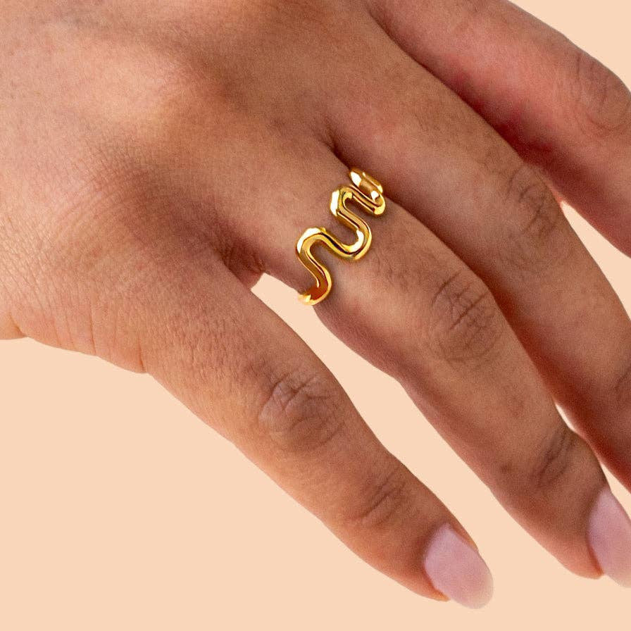 Gold ring on a hand against a beige background