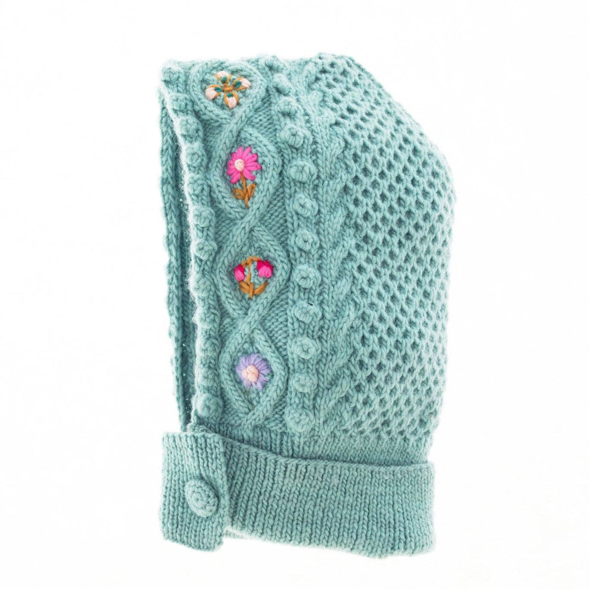 A light teal knit bonnet with a cable-knit pattern, featuring three colorful embroidered flowers on the side and a buttoned cuff.