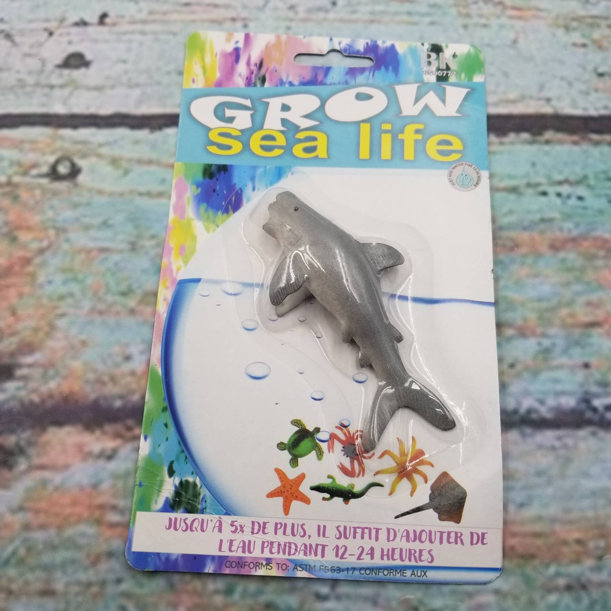 Toy shark figure in packaging with 'Grow sea life' text on a textured background