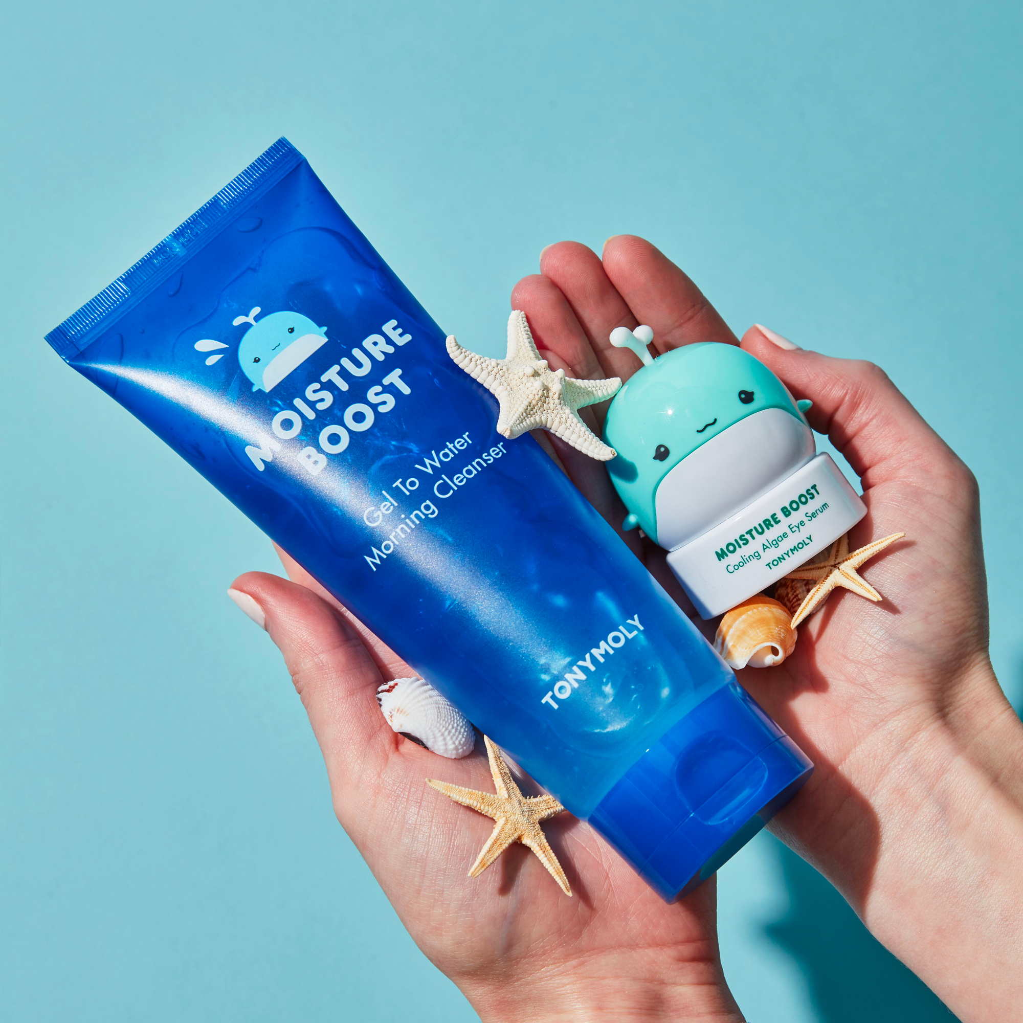 Two Tonymoly skincare products held by hands against a light blue background