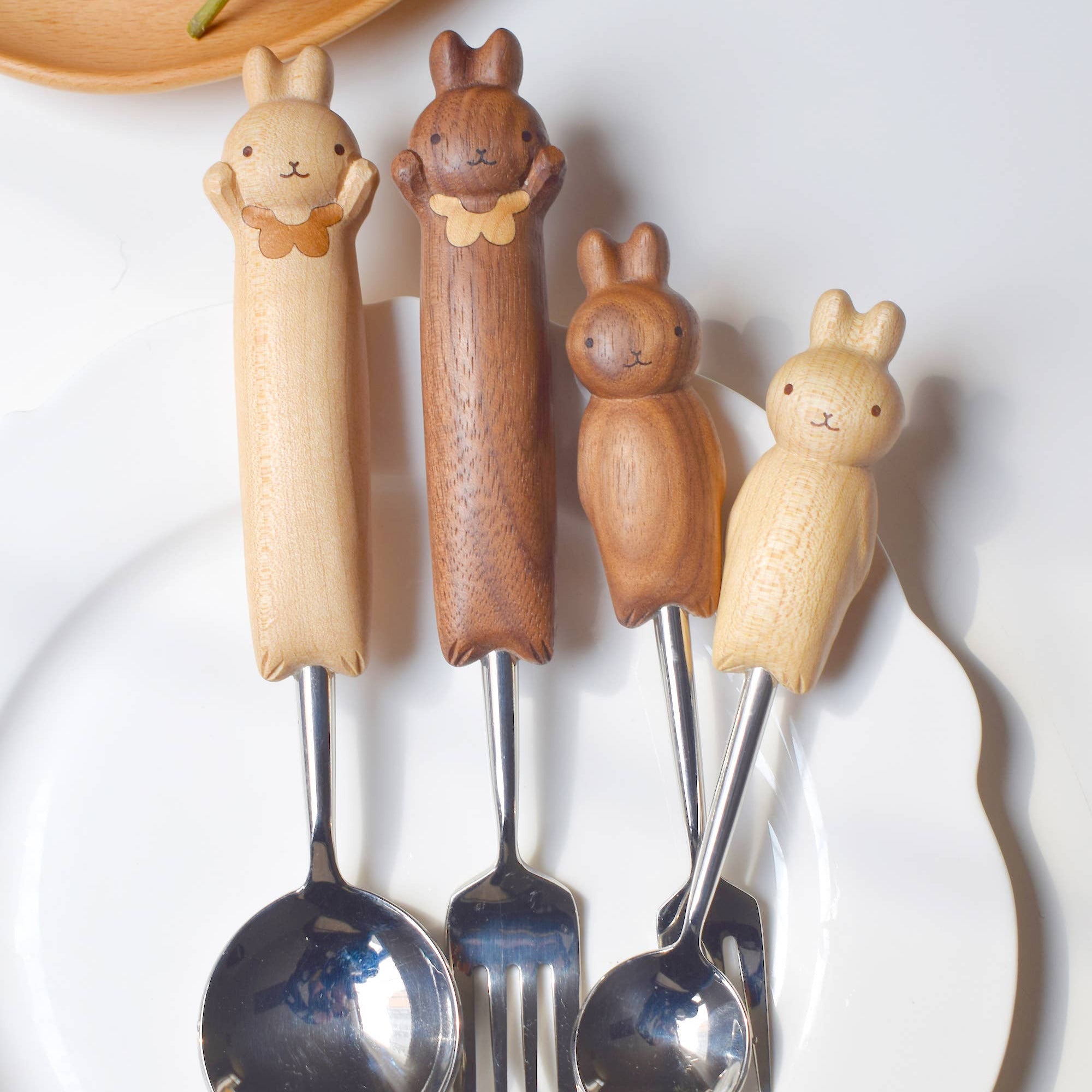 Set of four wooden-handled cutlery with animal designs on a white plate.