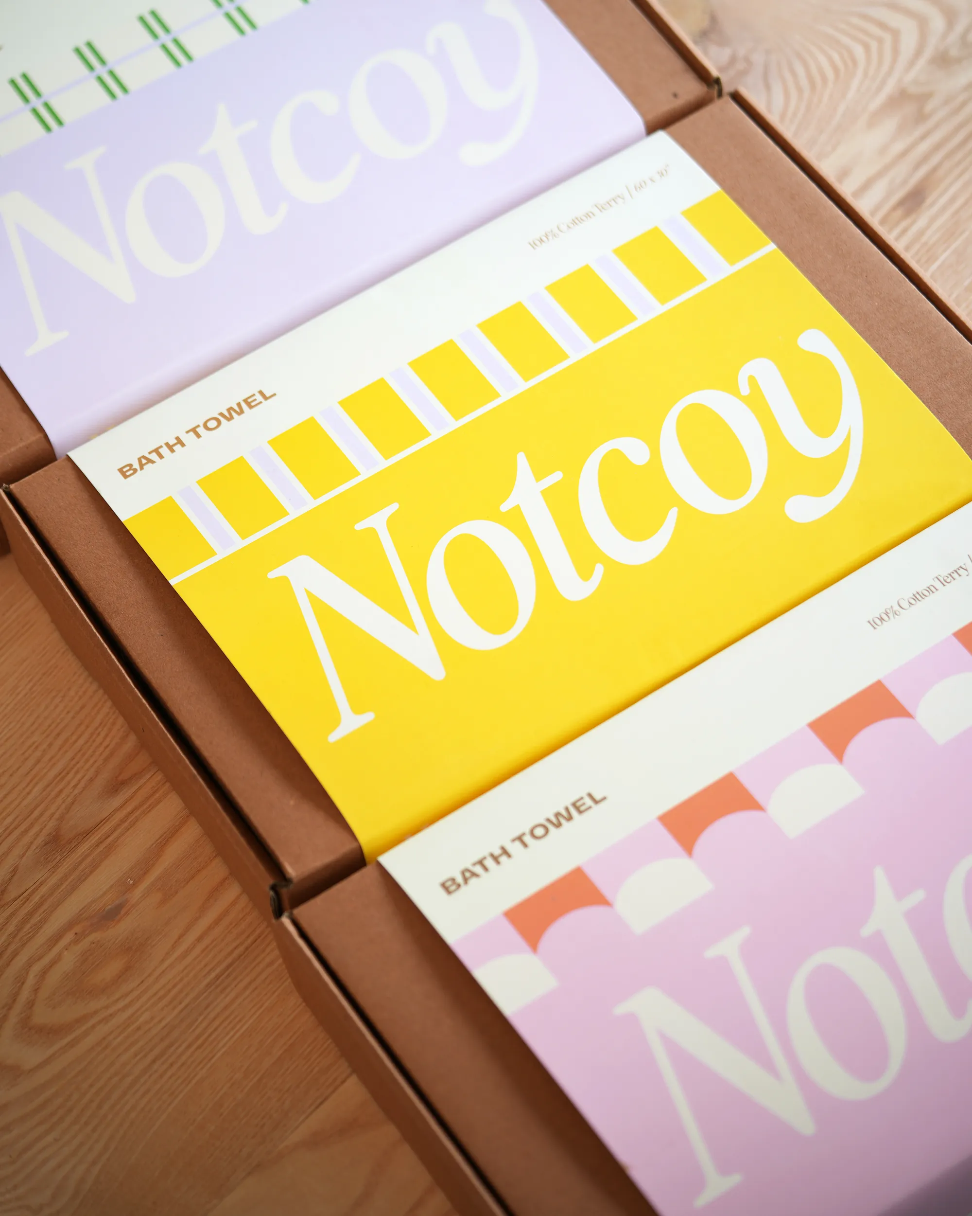 Bath towel packaging with 'Notcoy' branding on a wooden surface