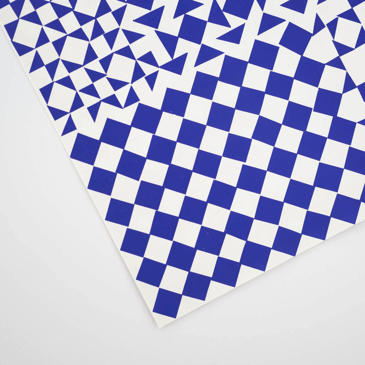 A square sheet of patterned paper or vinyl featuring a geometric design with a blue and white checkerboard and triangle motif, shown on a light gray background.