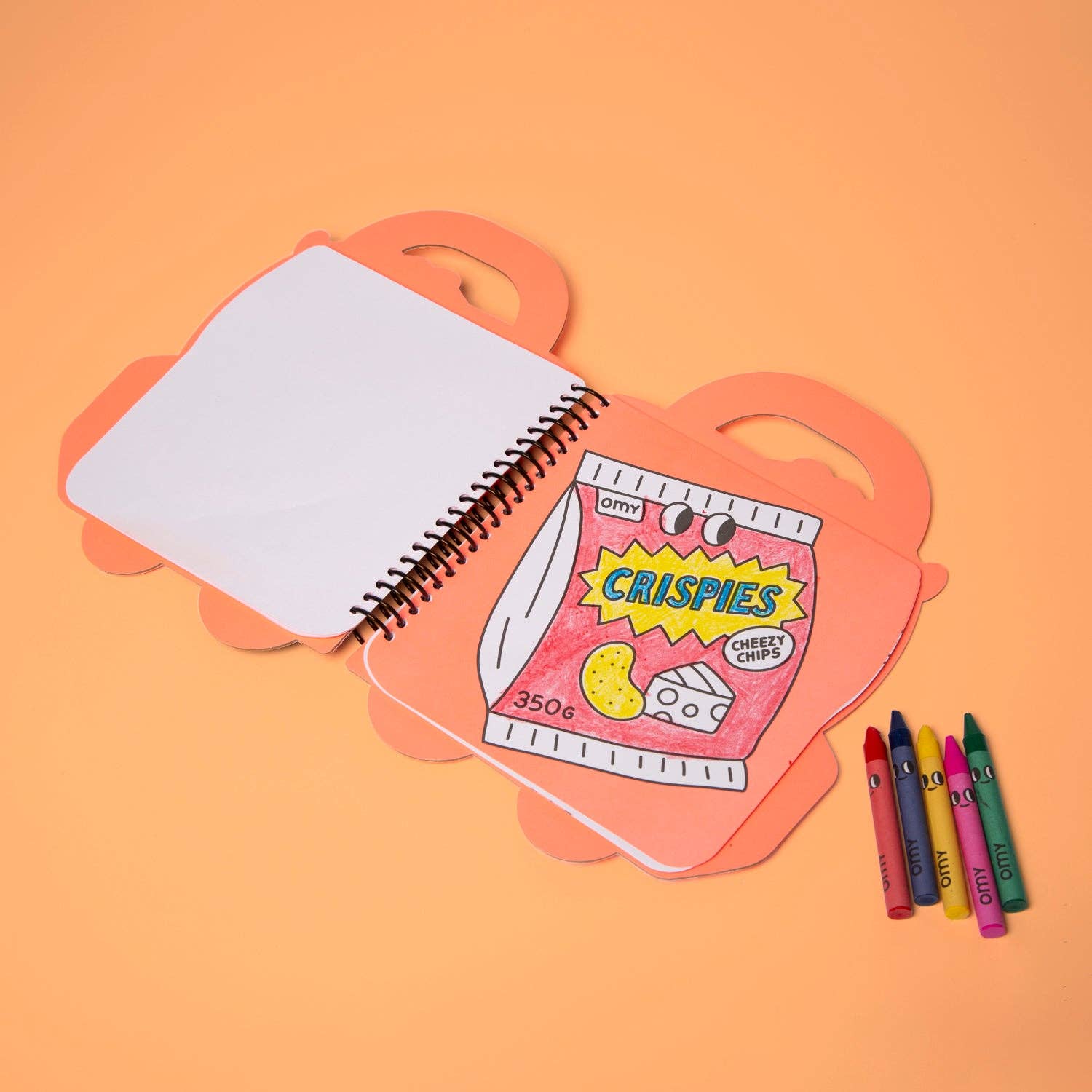 Notebook with a cracker-themed cover on an orange background, accompanied by crayons.