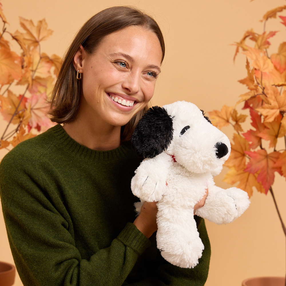 Woman holding a stuffed dog toy with a neutral background