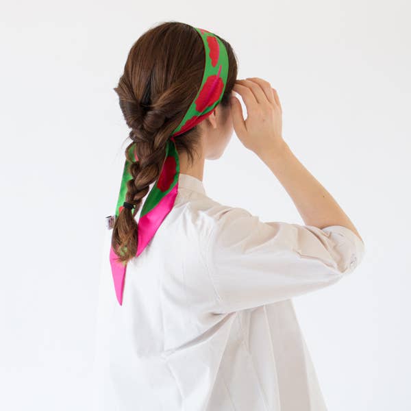 Person wearing a colorful headscarf with floral patterns on a white background
