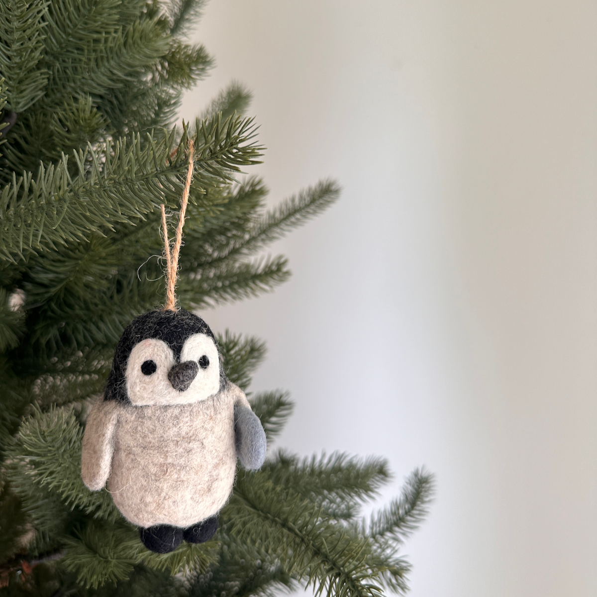 Felt penguin ornament hanging on a Christmas tree