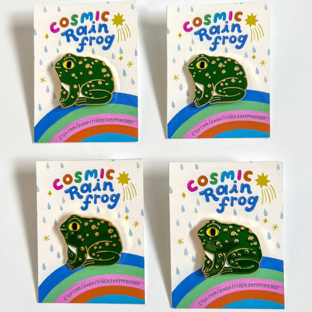 Four packaging designs of a 'Cosmic Rain Frog' product with a frog illustration on a rainbow background.