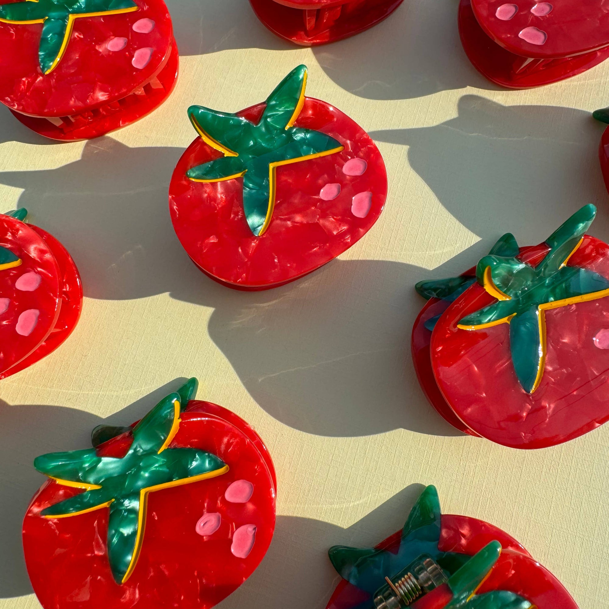 Red tomato-shaped objects with green leaves on a beige background
