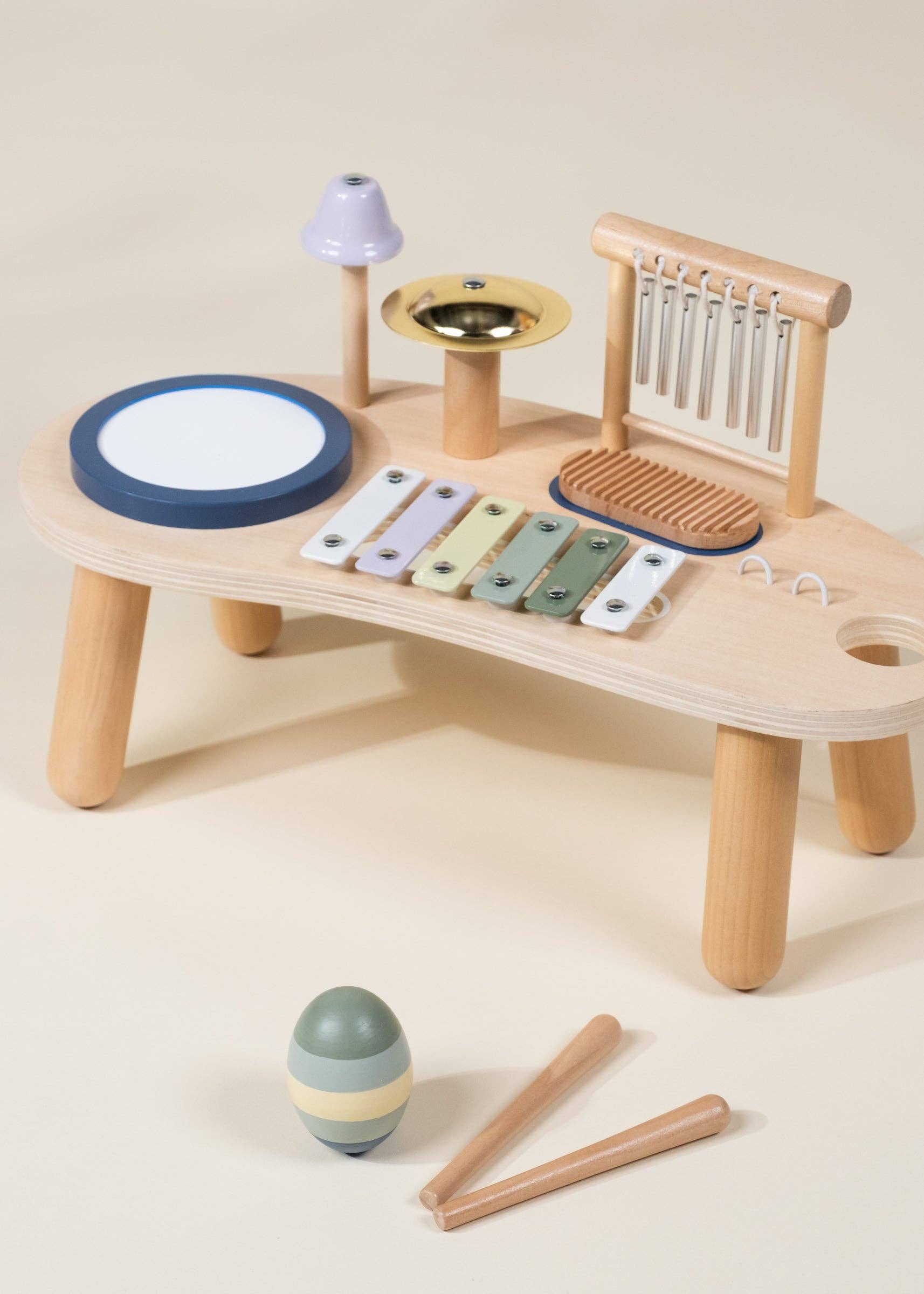 Wooden toy music set with various instruments on a beige surface