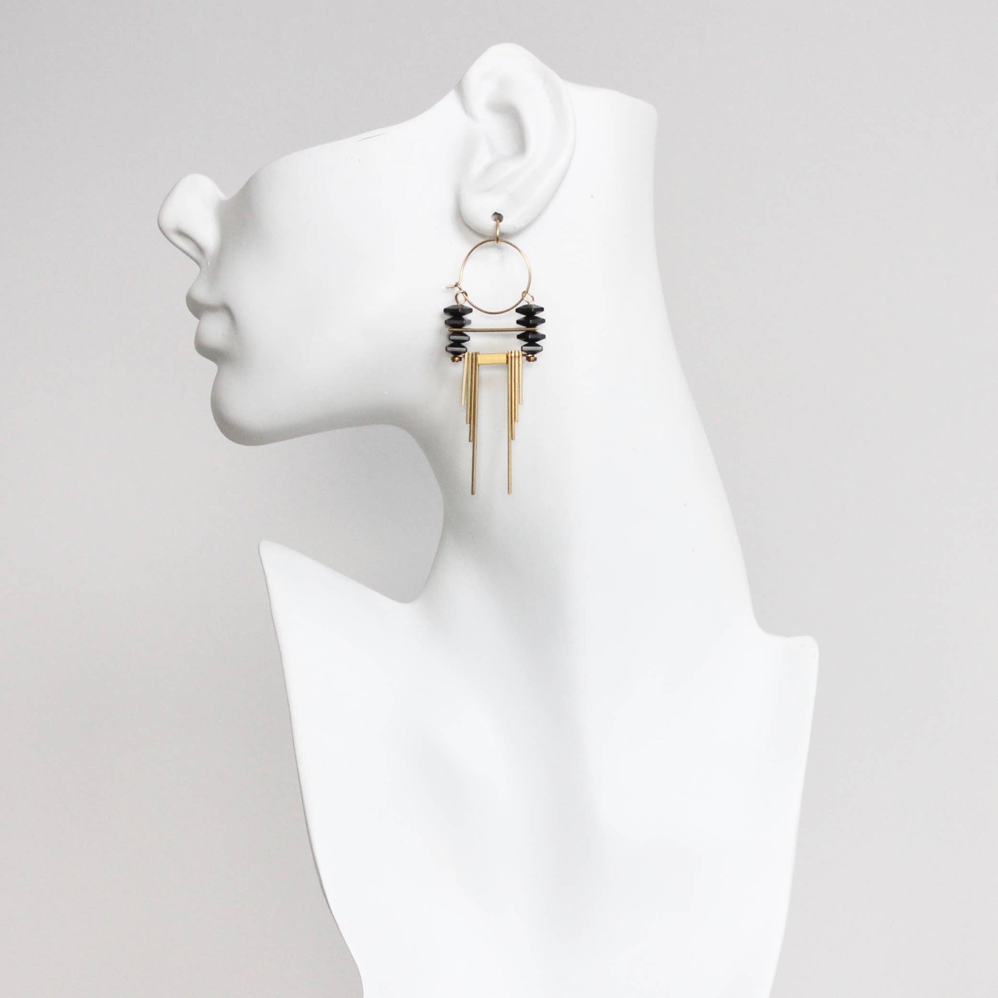 Earring displayed on a mannequin ear with a plain background