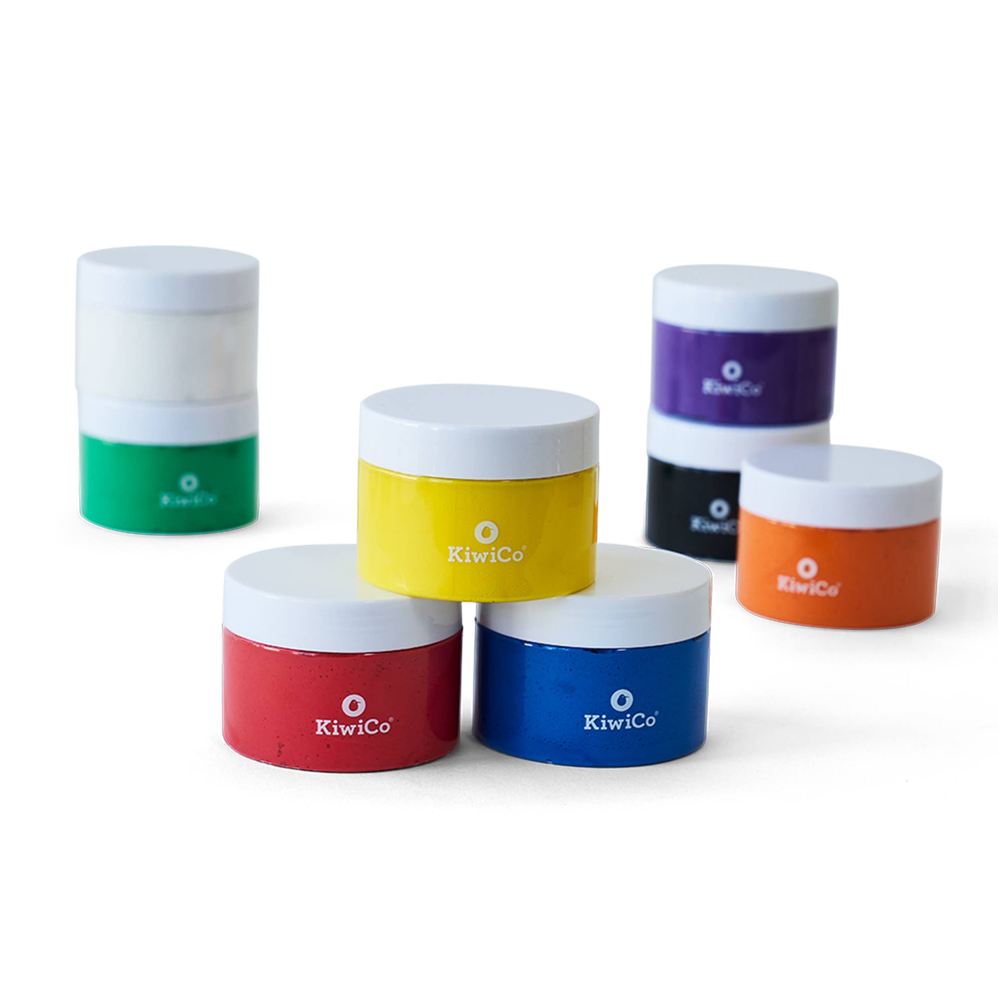 Six small round cosmetic jars with white lids and colorful lower bodies in green, yellow, black, orange, red, and blue, arranged on a white background. The brand name KiwiCo is printed on the front of each jar.