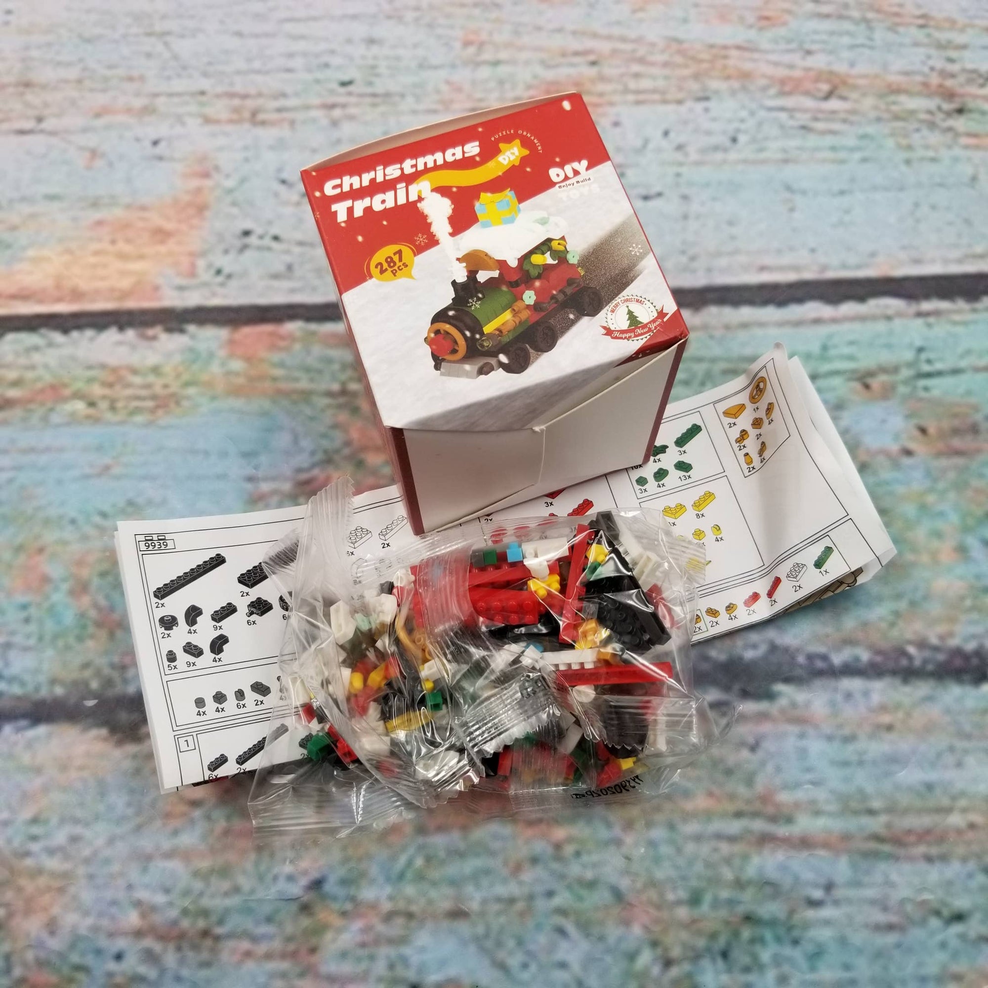 Toy Christmas train set with packaging and instructions on a textured surface