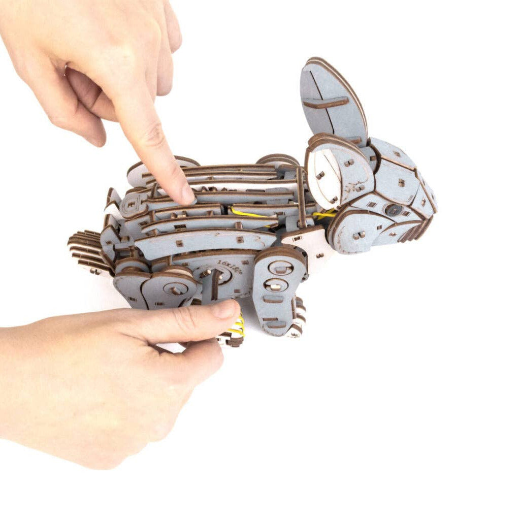 Mechanical rabbit model being manipulated by a hand on a white background